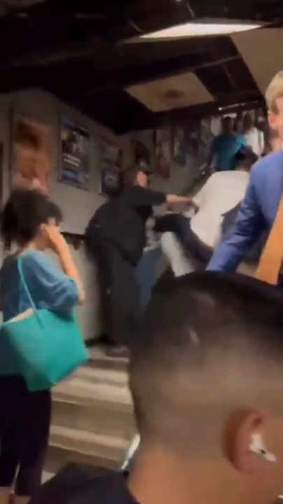 In UK, a black man hits a white man who's holding a baby, who falls to ground