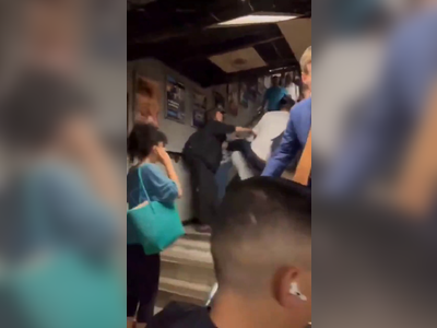 In UK, a black man hits a white man who's holding a baby, who falls to ground